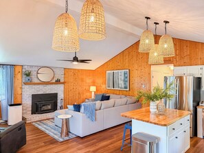 A modern living room with a fireplace, sofa, and wooden ceiling.