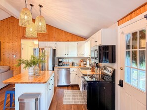 A modern kitchen with wooden cabinetry, stainless steel appliances, and a large island with a sink.