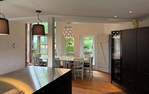 Eine moderne Küche mit einer großen Kochinsel, einem Holzespeisetisch und Stühlen, mit Blick auf Grünflächen.