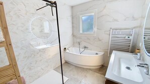 Ein modernes Badezimmer mit einer freistehenden Badewanne, einem Waschtisch mit Spüle, einem Spiegel und einem Handtuchhalter.