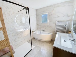 Ein modernes Badezimmer mit einer freistehenden Badewanne, einem Waschtisch mit Spüle, einem Spiegel und einem Handtuchhalter.