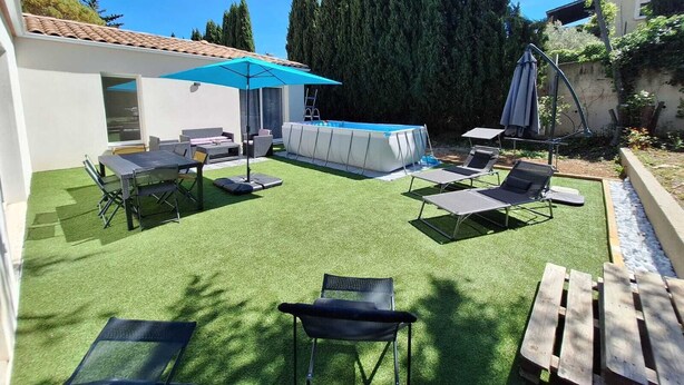 Eine Außenpatio mit Kunstgrasanlage, einem Pool und Liegestühlen.