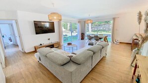 Ein modernes Wohnzimmer mit einer großen Couch, einem Flachbildfernseher und einem Essbereich mit Stühlen und einem Tisch.