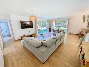 Ein modernes Wohnzimmer mit einer großen Couch, einem Flachbildfernseher und einem Essbereich mit Stühlen und einem Tisch.