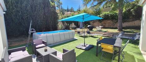 Un jardin avec une pelouse artificielle, une piscine, du mobilier d’extérieur et un espace barbecue.