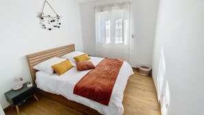 Ein Schlafzimmer mit einem hölzernen Bett, weißer Bettwäsche und einer roten Tagesdecke.