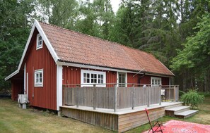 A red wooden cabin with a fenced deck and a small porch. - Lovely home in Tving with house a panoramic view (Tving)