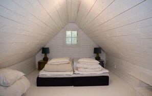 A small, sloped-roofed attic bedroom with a single bed, two bedside lamps, and a window. - Lovely home in Tving with house a panoramic view (Tving)