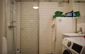 Een badkamer met een douche, wastafel en een wasmachine.
