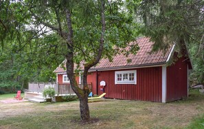 A red wooden cabin with a red roof, a basketball hoop, and a small deck. - Lovely home in Tving with house a panoramic view (Tving)