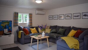 A cozy living room with a grey sofa, a small wooden table, and a window with curtains. - Lovely home in Tving with house a panoramic view (Tving)
