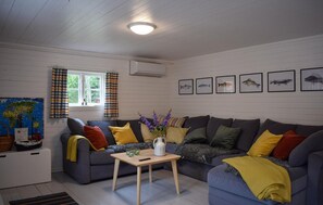 A cozy living room with a grey sofa, a small wooden table, and a window with curtains. - Lovely home in Tving with house a panoramic view (Tving)