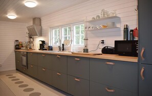 A modern kitchen with a built-in oven, a coffee maker, and a microwave on the counter. - Lovely home in Tving with house a panoramic view (Tving)