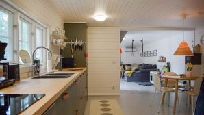 A modern kitchen with a wooden countertop, a sink, and a dining area with a table and chairs. - Lovely home in Tving with house a panoramic view (Tving)