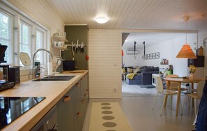 A modern kitchen with a wooden countertop, a sink, and a dining area with a table and chairs. - Lovely home in Tving with house a panoramic view (Tving)