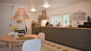 A kitchen with a wooden table, chairs, a hanging light fixture, and a window with a view. - Lovely home in Tving with house a panoramic view (Tving)