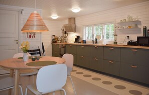 A kitchen with a wooden table, chairs, a hanging light fixture, and a window with a view. - Lovely home in Tving with house a panoramic view (Tving)