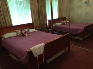 Quarto com duas camas, uma cabeceira de madeira, uma cadeira e um espelho.