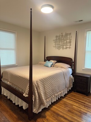 A four-poster bed with a wooden frame, a quilted bedspread, and a decorative pillow. - Charming little house (Richmond)