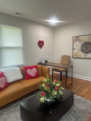 A living room with a sofa, coffee table, and a painting on the wall. - Charming little house (Richmond)