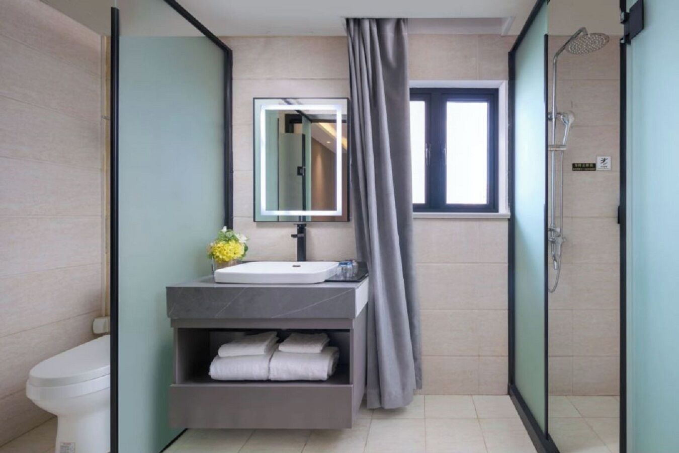 Un baño moderno con ducha, inodoro, lavabo con espejo y toallero.
