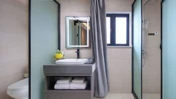 A modern bathroom with a shower, a toilet, a sink with a mirror, and a towel rack.