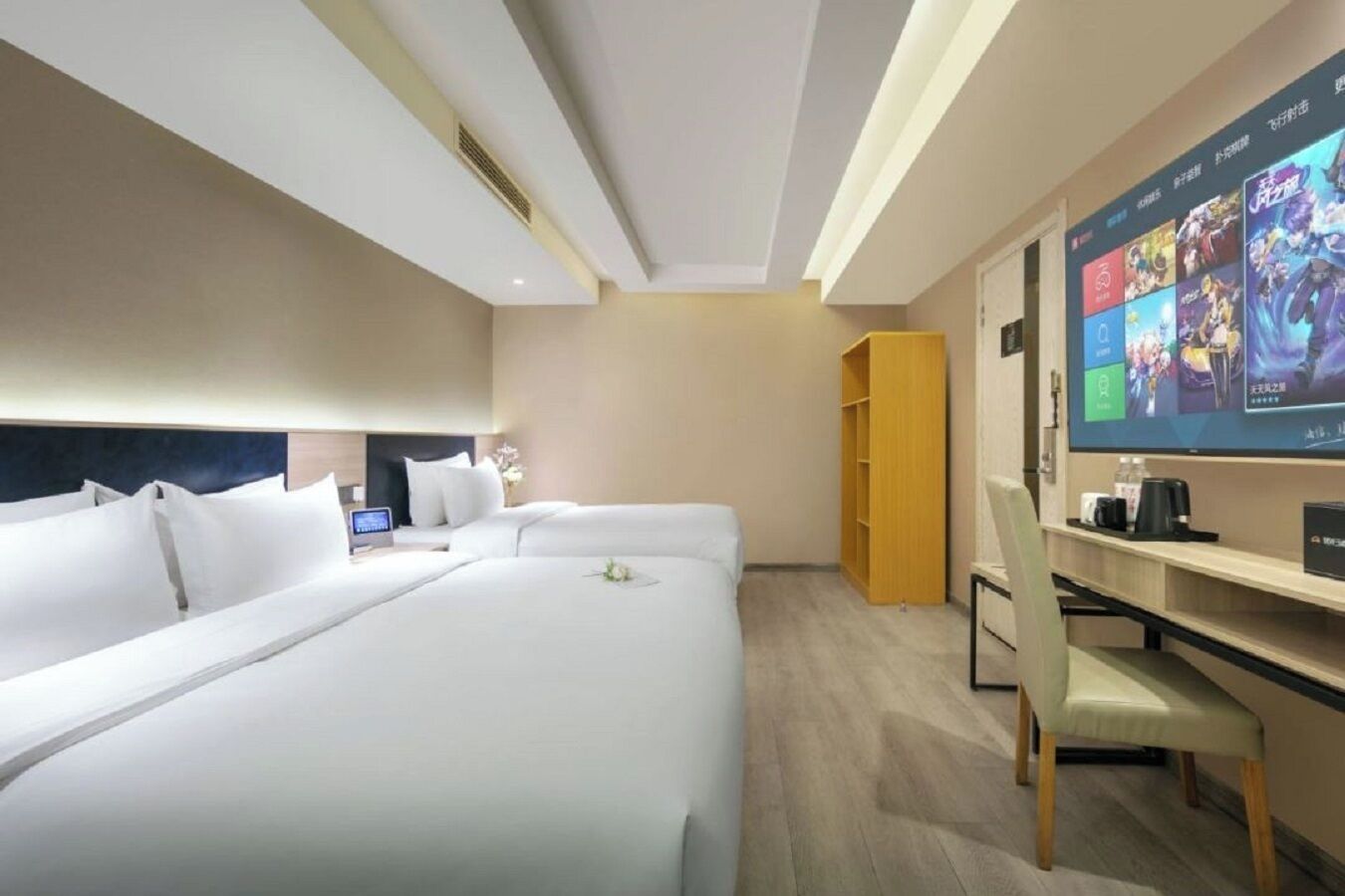 Quarto de hotel com duas camas, televisão, escrivaninha e guarda-roupa.