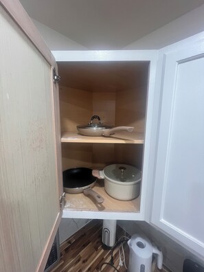 Ein Küchenschrank mit einer Mikrowelle, einer Pfanne und einem Topf auf der unteren Ablagefläche.