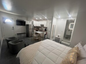 Ein kleines Hotelzimmer mit Bett, einer Küchenzeile, einer Sitzecke und einem Badezimmer.