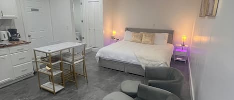 A modern hotel room with a bed, a desk, and a chair.