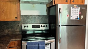 A kitchen with wooden cabinets, a stainless steel stove, and a refrigerator.