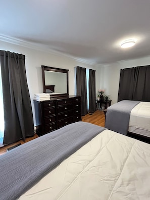 A bedroom with a bed, a dresser, a mirror, and curtains.