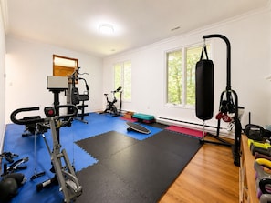 A gym with exercise equipment, mats, and a punching bag.