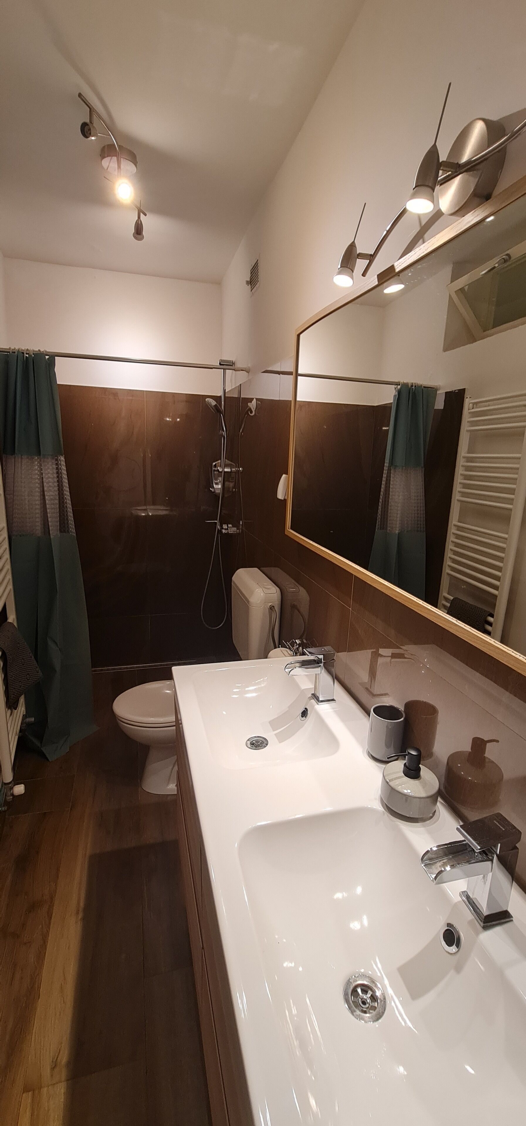 Une salle de bain moderne avec un grand miroir, une baignoire et des toilettes.