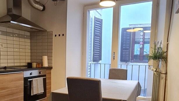 Et moderne køkken med træskabe, en indbygget ovn og et spiseområde med et bord og stole.