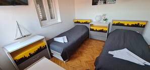 Ein Schlafzimmer mit zwei Betten, einem Nachttisch, einer Kommode und einem Fenster mit Jalousien.