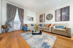 Ein modernes Wohnzimmer mit einer Sofagarnitur, einem Couchtisch und einem großen abstrakten Gemälde.