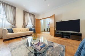Ein modernes Wohnzimmer mit einer Couch, einem Glastisch und einem Flachbildfernseher.