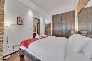 Ein Hotelzimmer mit einem großen Bett, einer Ziegelwand, einem Holzschrank und einer Stehlampe.