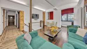 Amplia sala de estar con techo alto, una mesa de comedor con sillas y un juego de sofá verde.