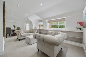 Ein geräumiges Wohnzimmer mit hoher Decke, einem großen Fenster mit Blick und einer Couch sowie einem Couchtisch.