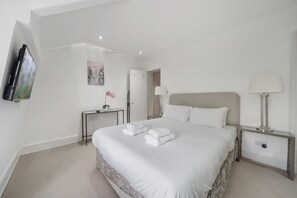 Ein Hotelzimmer mit einem großen Bett, einem Nachttisch mit Lampe, einem wandmontierten Flachbildfernseher und einem Wandbild.