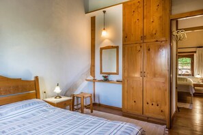 Une chambre à coucher comprenant un lit, une table de chevet, une lampe, une armoire en bois, un miroir et une fenêtre.