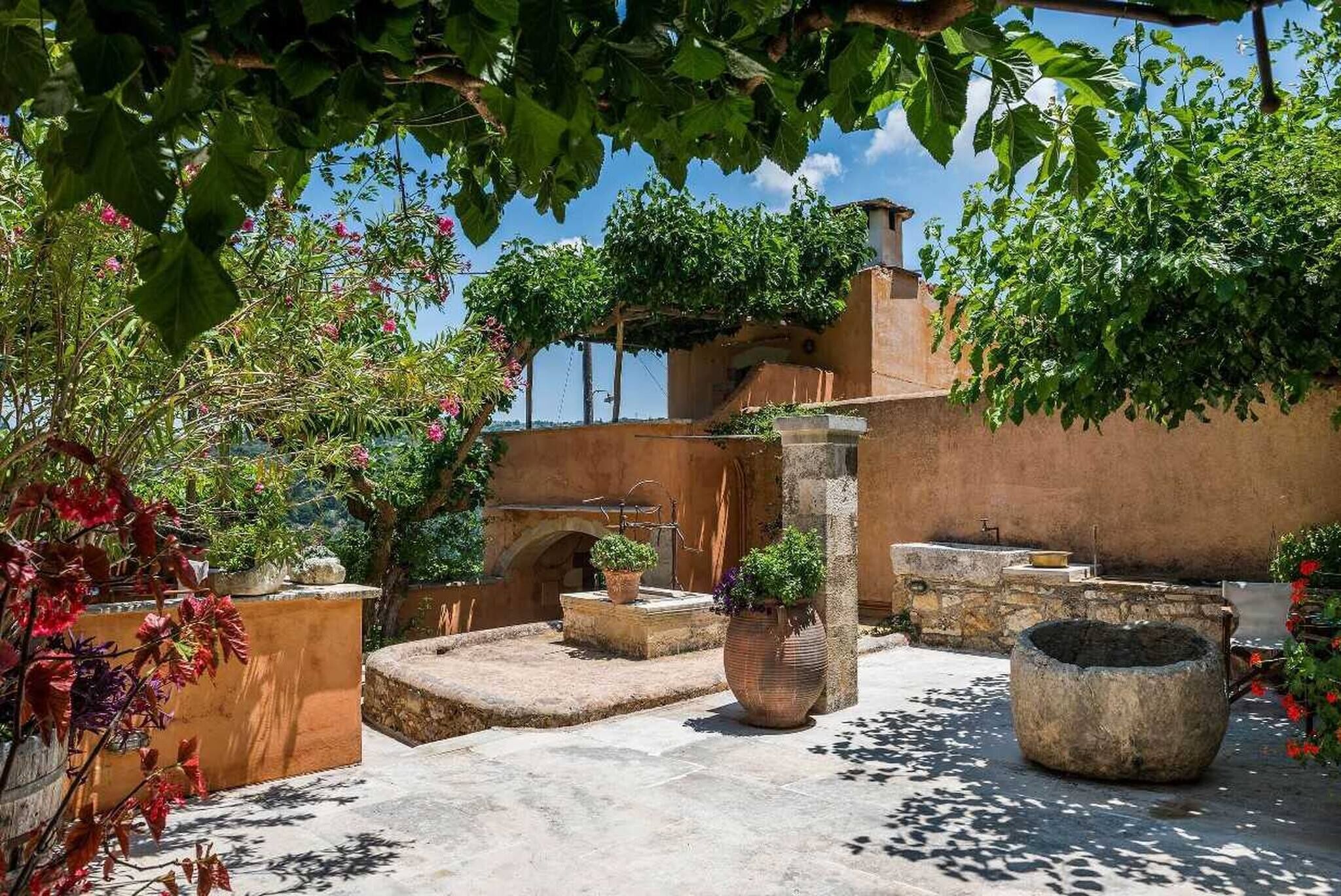 A courtyard with stone planters, a fountain, and a building with arches.