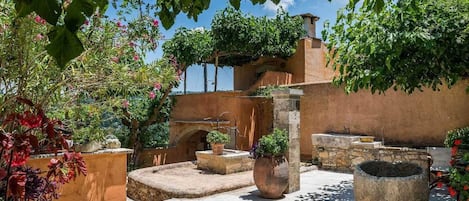 A courtyard with stone planters, a fountain, and a building with arches.