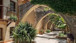 Un patio al aire libre con arcos de piedra, plantas en macetas y un sendero.