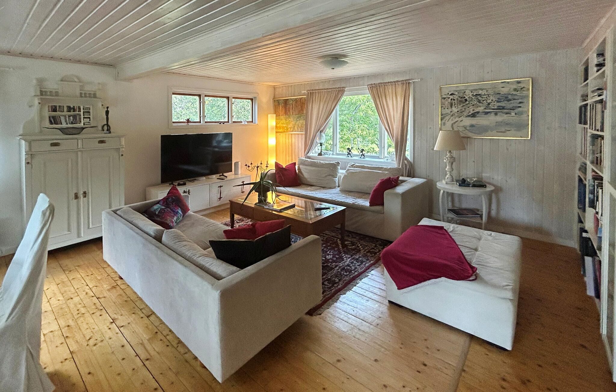Una sala de estar con sofá, mesa de centro, televisor y estantería.