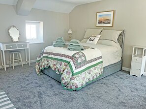 Ein Schlafzimmer mit Bett, Schreibtisch, Stuhl und Fenster.
