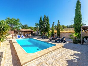 A swimming pool with lounge chairs, a stone patio, and a rustic building.