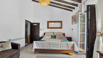 Une chambre à coucher avec un lit, une tête de lit en bois, un luminaire suspendu, une porte et une fenêtre.